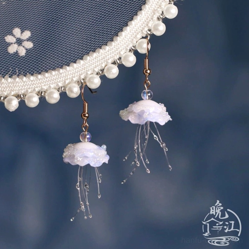 Pair of iridescent jellyfish Hanfu drop earrings with transparent beaded tentacles displayed beside a pearl-trimmed traditional Chinese Hanfu accessory on a dark blue background