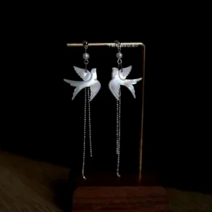 Iridescent white shell swallow tassel earrings with pearl accents and long silver chain pendants displayed on a wooden jewelry stand, elegant Chinese Hanfu jewelry