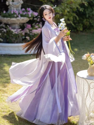 Rear three-quarter view of iris purple Song style Hanfu with sheer flowing wrap skirt and long lavender fairy cardigan outdoors