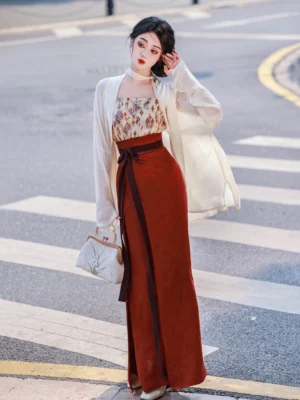 Full-body front view of a woman wearing a modern Song Dynasty Hanfu set with cream wing sleeves, printed beige camisole, deep red wrap skirt, and dark brown waist sash on an urban street