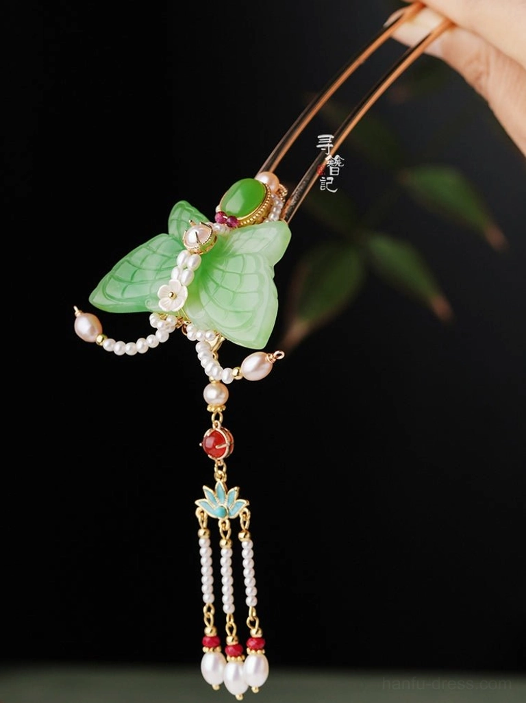 Close-up side view of a Chinese Hanfu butterfly hair pin with jade-look ornament red gemstone-style accents pearl tassels and lotus details