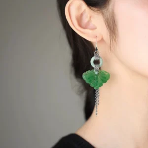 Jade butterfly drop earrings worn on ear, showing elegant silver tassel movement and Chinese-inspired hook earring profile