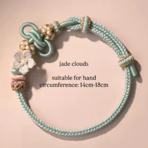 Jade Clouds handwoven Chinese knot bracelet in mint green braided cord with gold accents, flower pearl charm and colorful beads on light pink background