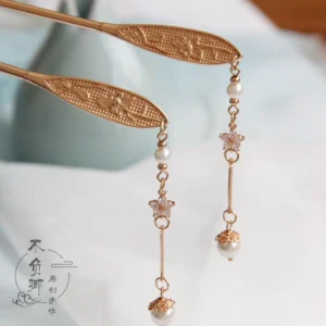 Vintage Chinese hair stick with antique gold floral carving, pearl-like beads, zircon accents, and dangling tassel displayed on light gray fabric