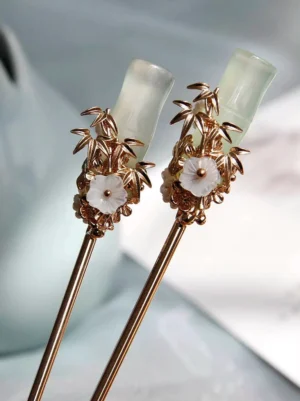Close-up of jade green bamboo Chinese hair sticks with gold bamboo leaves white flower and slender hairpin shafts