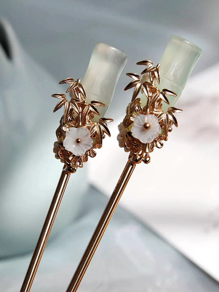 Close-up of jade green bamboo Chinese hair sticks with gold bamboo leaves white flower and slender hairpin shafts
