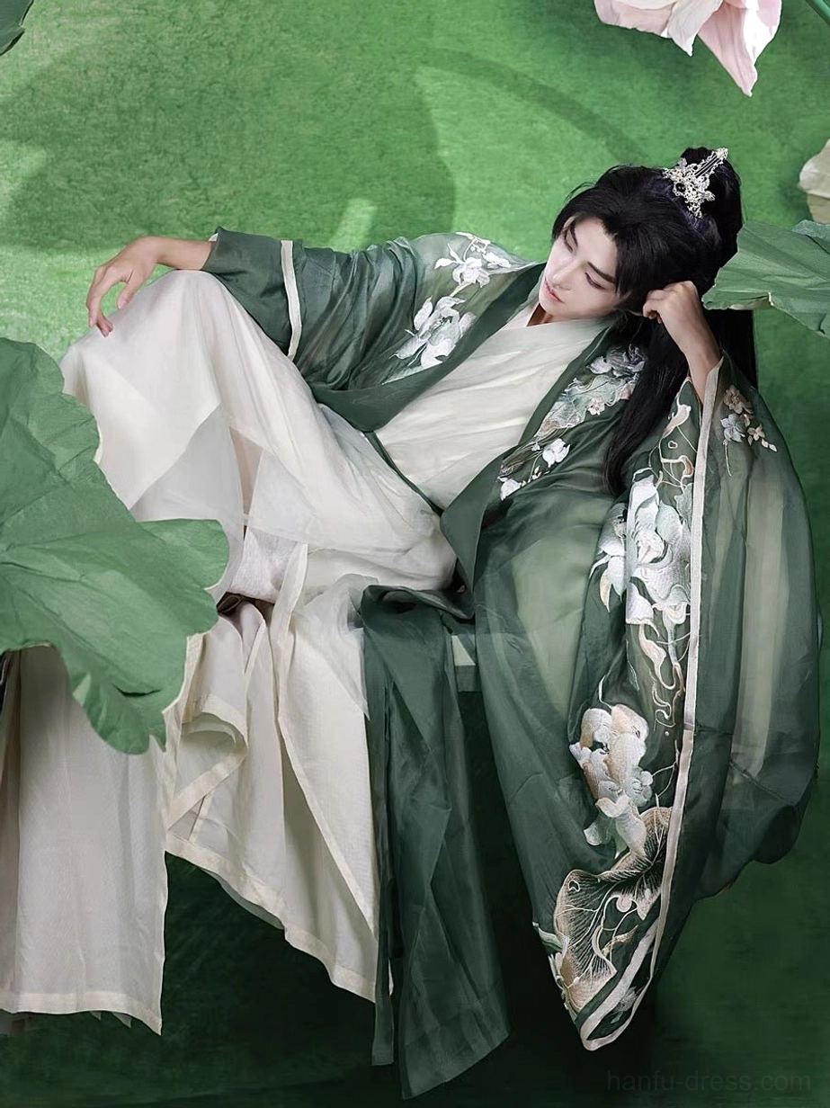 Male model wearing a jade green and ivory Jade Lotus men's Hanfu complete set with layered cross-collar robes, lotus embroidery, wide sleeves, and a flowing xianxia-inspired coat