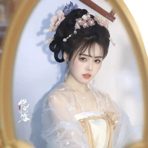 Model wearing a jade orchid Chinese hair pin with an elaborate Hanfu hairstyle and pink Tang-style outfit in a vintage gold mirror