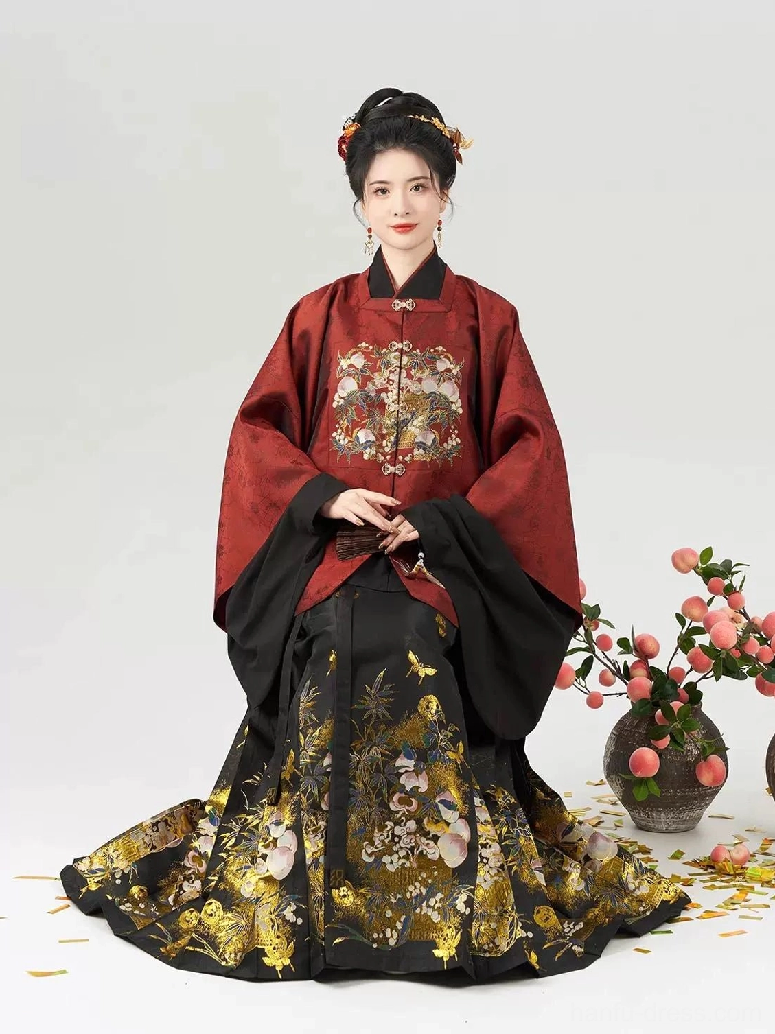 Elegant seated model wearing Jade Peach Spirit Ming style Hanfu Chinese New Year dress with floor length printed mamian skirt