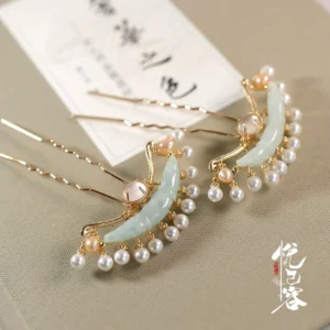 Classical Chinese jade pearl hair pin displayed on linen with vintage calligraphy paper, gold toned metal frame, pale green crescent jade ornaments, white pearl clusters, and golden accent beads