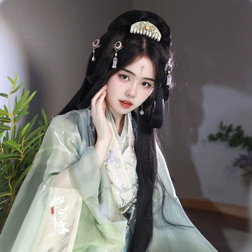 Close up portrait of woman in light green Hanfu wearing jade green hair comb and tassel hairpin with gold floral pearl details