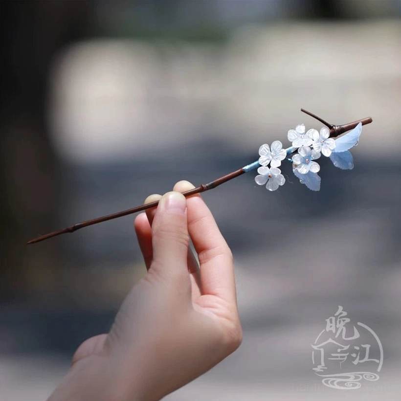 Three-quarter handheld view of blue white plum blossom Chinese hair stick with brown stick and blue thread wrapping