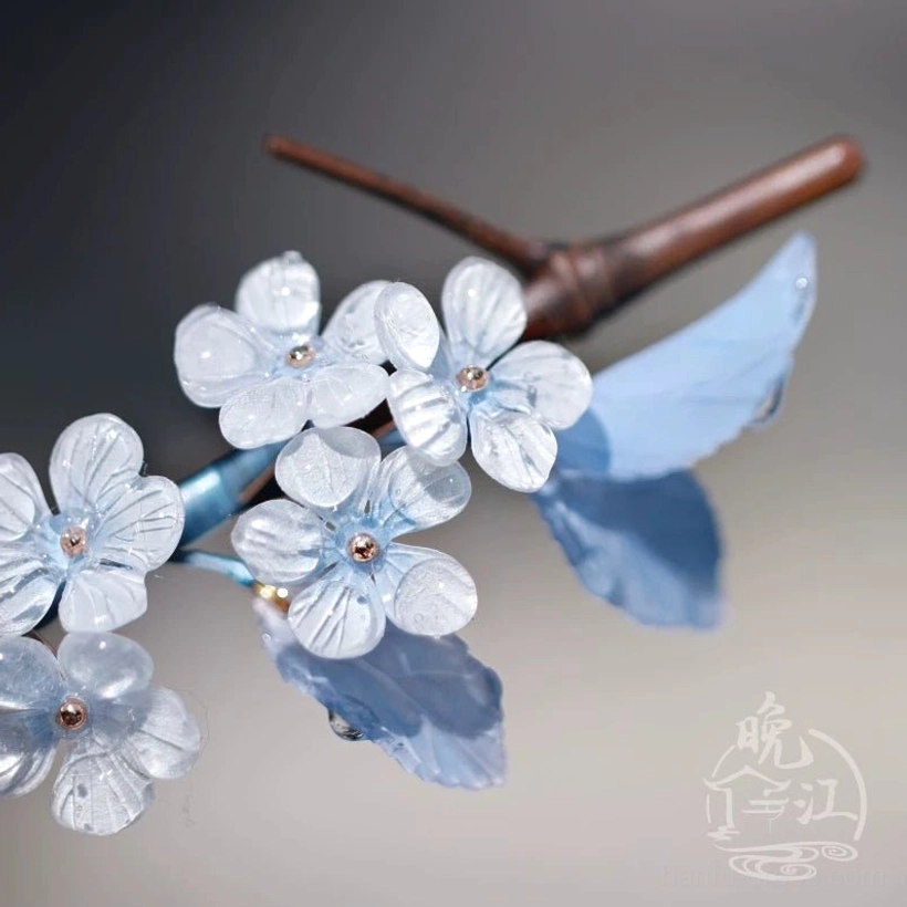 Detailed floral ornament of Jade Skies Chinese hair stick with glossy blue leaves and pale blue white blossoms