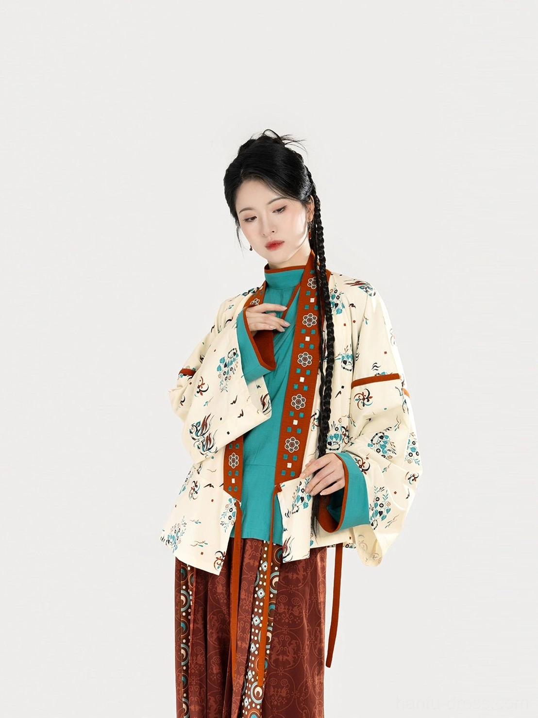 Close-up of layered Jin Dynasty-inspired Hanfu tops showing a printed outer jacket, reddish-brown trim, and solid teal curved-collar inner top