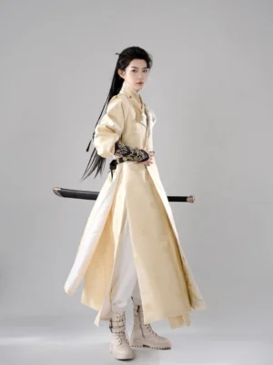 Back three quarter view of Jingling Tang Dynasty inspired hanfu for men showing layered beige robe split hem sleeveless vest and warrior styling