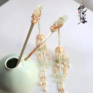 Juhua floral tassel hairpin with jade green beads imitation pearls and gold toned metal displayed on a green ceramic vase