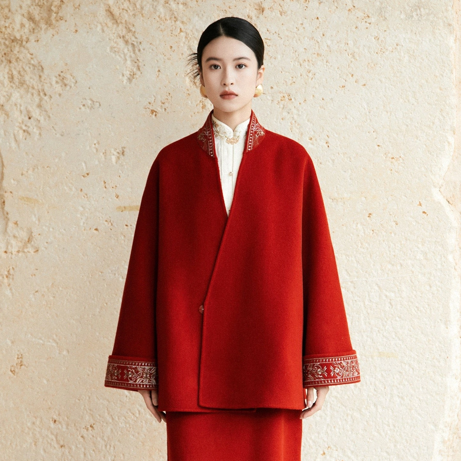 Front view of jujube red Hanfu inspired wool coat with wrap style closure embroidered trims and matching skirt styling