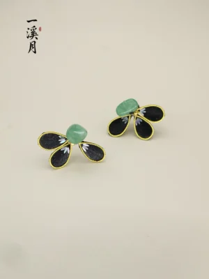 Front view of black and gold Chinese floral stud earrings with irregular green jade-style center stones and delicate petal patterns
