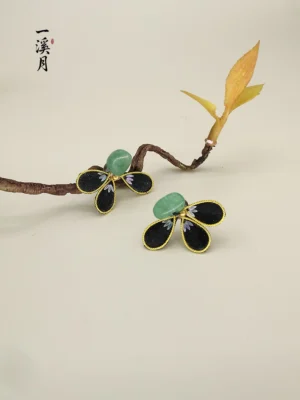 Chinese floral stud earrings with jade-green center stones and black gold-edged petals styled with an oriental decorative twig