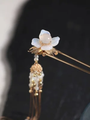 Close-up of Lady Yu Chinese hair stick floral ornament with luminous white petals pearl-like bead and gold tassel