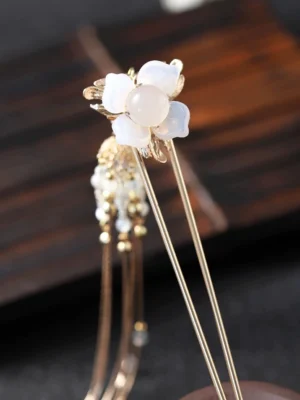Lady Yu floral tassel Chinese hair stick with opalescent white flower pearl-like center and gold double prongs on wooden background