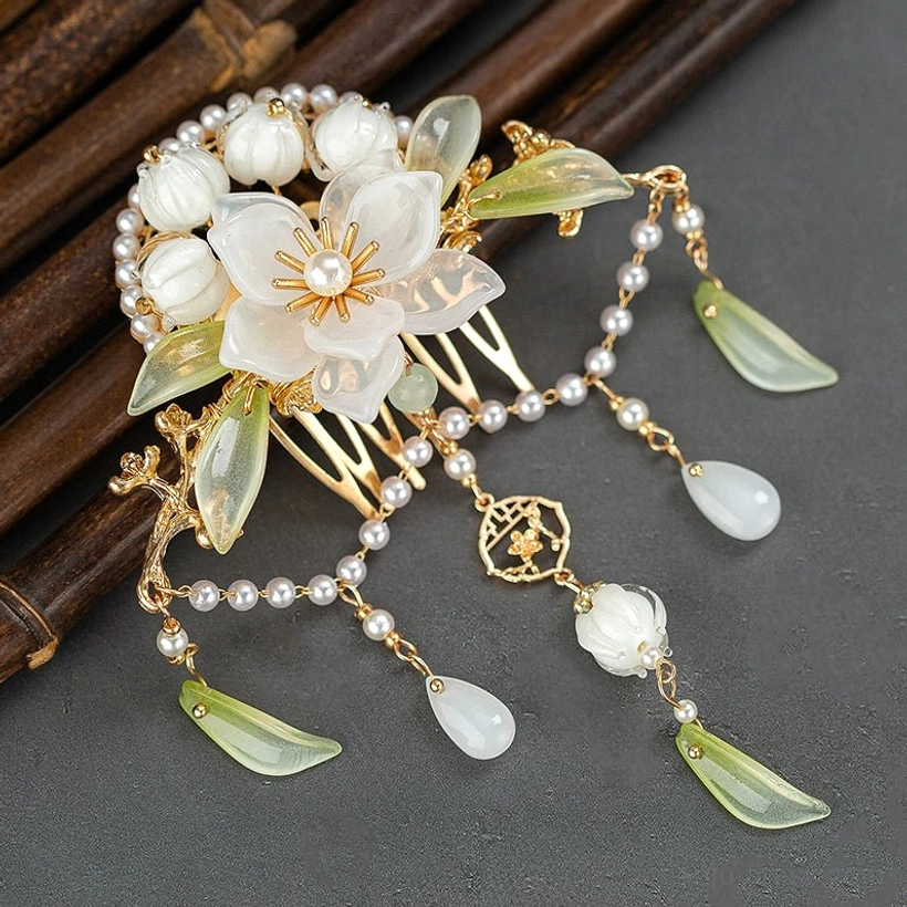 Top view of Lanling camellia pearl tassel Hanfu hair pin showing gold openwork charm, white flower, green jade style leaves and teardrop pendants