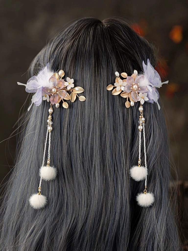 Lavender floral Hanfu hair clips worn on a styled updo, showing pearl tassels and white pom-pom hair ornaments from the back