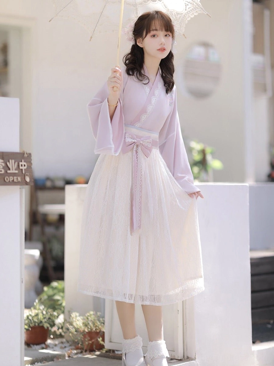 Full-length lavender modern Hanfu midi dress featuring a cross-collar bodice, off-white lace skirt and sweetheart bow sash