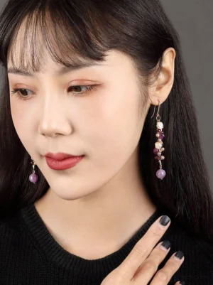 Model wearing lavender pearl drop Chinese earrings with purple gemstone-style beads and gold-tone hook ear wires