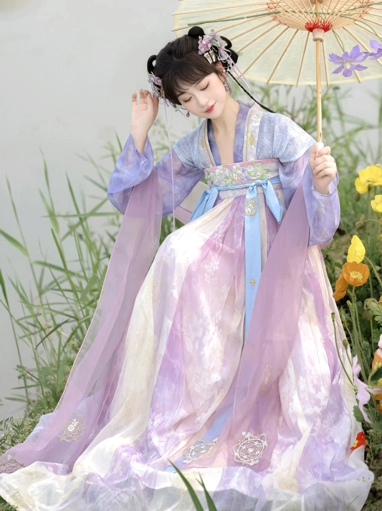 Low angle side view of a lavender pink cream Qixiong Ruqun Hanfu dress with sheer sleeves and flowing shoulder veils beside a garden umbrella