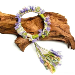 Lavender purple Tibetan-inspired handwoven Chinese bracelet with green cream knotwork and long multicolor fluffy tassels on driftwood