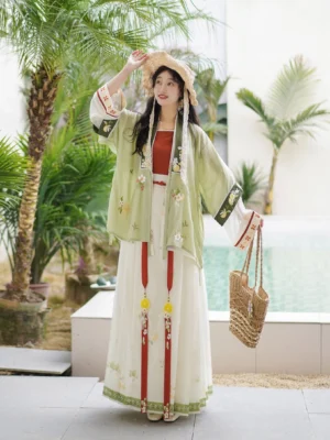 Front full-body view of a woman wearing a Lemon Black Tea Song Dynasty Hanfu Qiyao ruqun with a mint green embroidered outer jacket, cream pleated skirt, red waist ties, and yellow tassel pendants