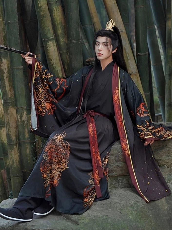 Male model wearing a complete Leo-inspired Wei-Jin Wuxia Hanfu set in black, red, and gold while seated on a stone in a bamboo grove, showing wide sleeves, flame-inspired decoration, and a red waist sash