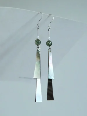 Letter from the Wind green shell tassel Chinese hook earrings displayed on a white board with silver hooks and speckled green beads