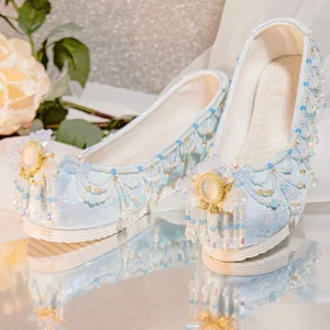 Light blue beaded traditional Chinese Hanfu shoes with upturned toes, golden ornaments, pink floral accents, blue tassels, and white platform rubber soles