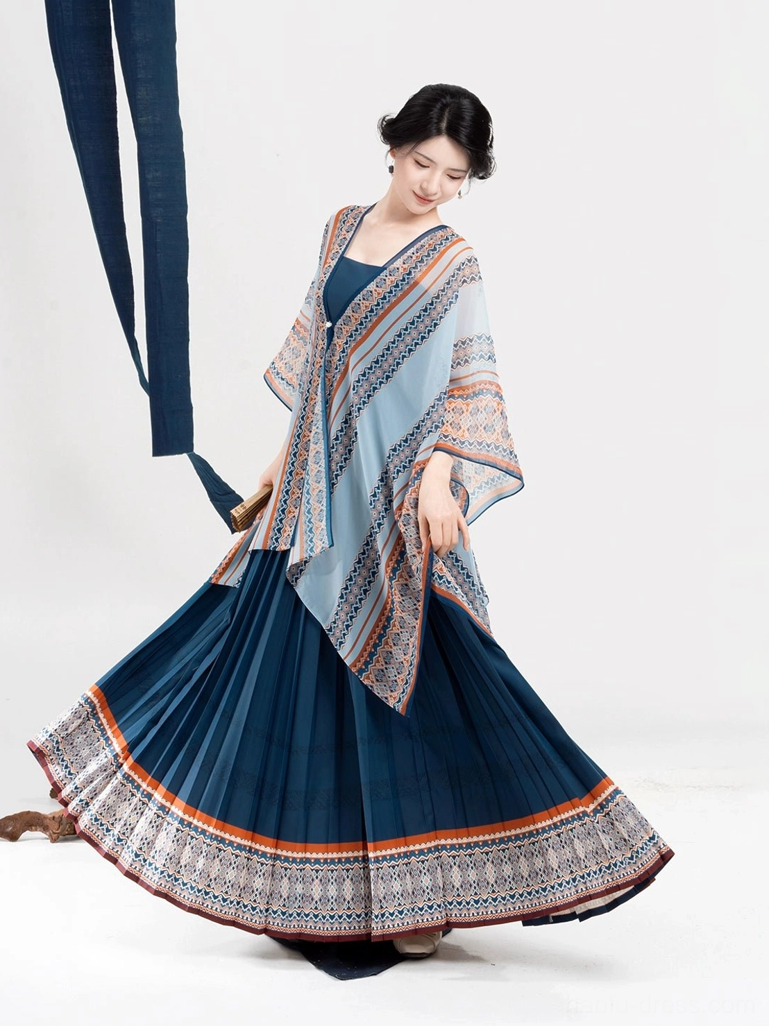 Front three-quarter view of a light blue Dong-inspired Hanfu shawl layered over a dark blue camisole-style pleated dress
