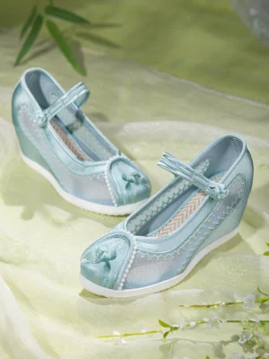 Light blue embroidered Chinese Hanfu shoes with breathable mesh and satin upper, bow detail on the rounded toe, Chinese disc buckle ankle strap, internal wedge heel, and white rubber outsole