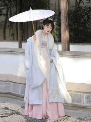 Light blue and pink Tang Dynasty Qixiong Ruqun hanfu costume with white fur trim, wide Da Xiu Shan sleeves, floral embroidery, and flowing skirt styled with a white oil-paper umbrella