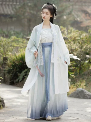 Front view of a light blue Song Dynasty Qiyao Ruqun Hanfu complete set with embroidered camisole, sheer wide-sleeved Beizi coat, gradient pleated skirt, blue waist sash, and tassel pendant in a classical Chinese garden