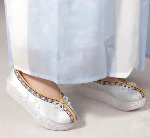 Light cyan Chinese Hanfu platform shoes shown worn with a flowing blue and white traditional Hanfu skirt, highlighting the elevated sole and decorative details