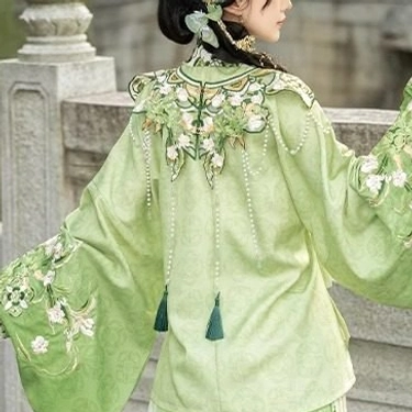 Close-up back detail of light green Ming style Hanfu upper garment showing floral embroidered cloud collar, sleeve cuffs, tassel pendants and jacquard texture