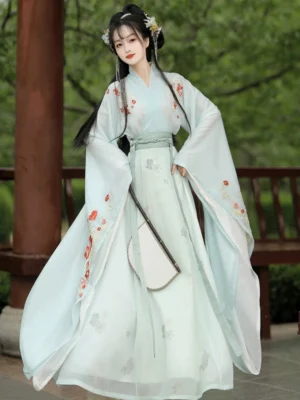 Light green Wei Jin Dynasty Qiyao Ruqun Hanfu with red floral embroidery, flowing skirt, wide sleeves, and round silk fan in a traditional garden pavilion