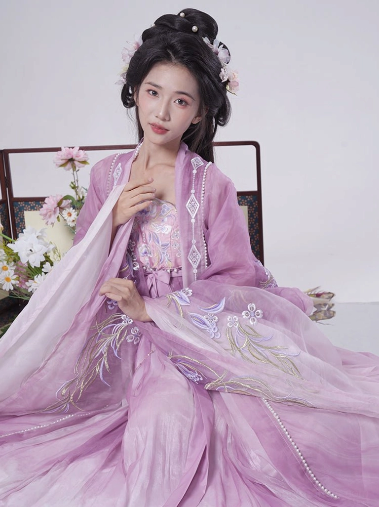 Light purple Tang Dynasty Hanfu Heziqun outfit shown in a seated portrait with floral embroidery, soft sheer layers, pearl-trimmed skirt hem, and flower hairpins