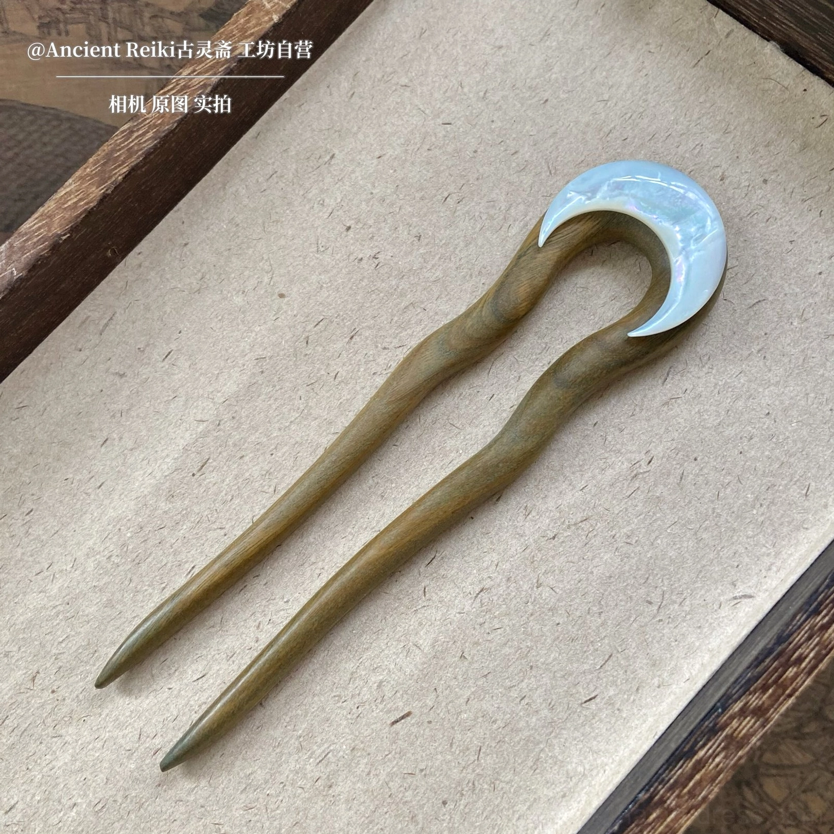 Light sandalwood-brown U-shaped Hanfu hair stick with natural wood-grain appearance and iridescent crescent moon inlay