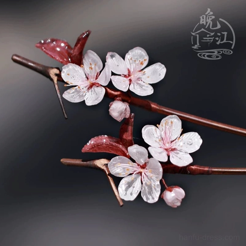Side flat lay of two Lihua plum blossom Chinese hair sticks with white five-petal flowers, pink buds, burgundy leaves, and brown branch-style stems