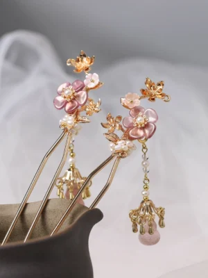Close-up of paired lilac cherry blossom Hanfu hair sticks with pink floral ornaments pearl details gold toned accents and pink tassel pendants