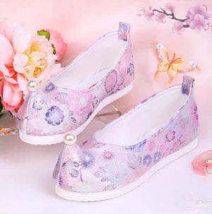 Lilac traditional Chinese Hanfu shoes displayed as a pair with upturned toes, floral pink purple brocade texture, pearl toe ornaments, white rubber soles, and rear pull tabs