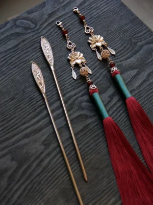 Traditional Chinese hair stick collection showing red tassel hairpins and engraved decorative hairpins on dark wood
