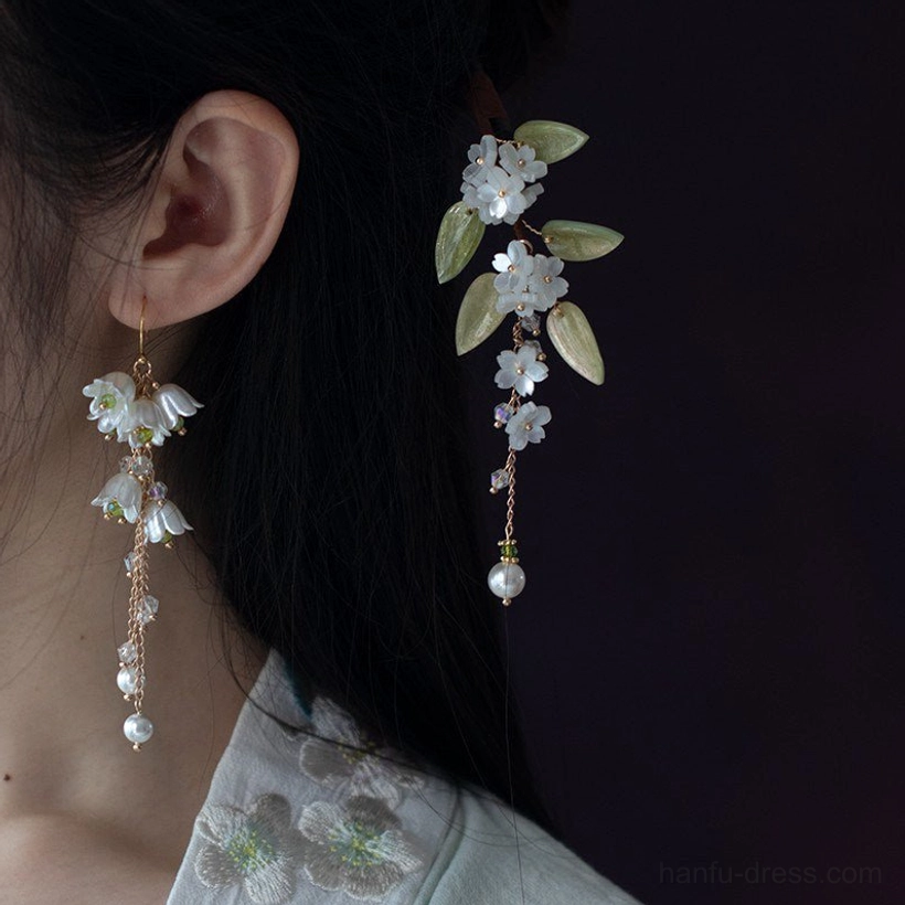 Close-up of lily of the valley Chinese earrings and retro floral earrings worn beside the ear with green leaves, flower charms, and pearl accents