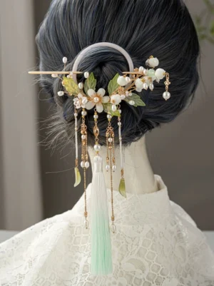 Lily of the valley hanfu back hair pin worn on a dark hair bun with white flower clusters gold chains pearl accents and flowing tassels